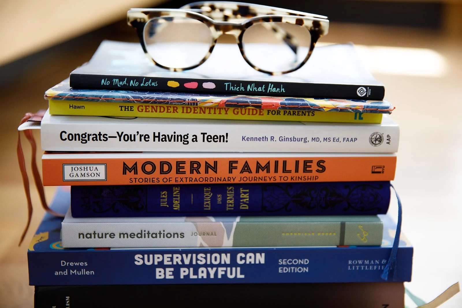 Stack of eight books about parenting, growth, and mindfulness with eyeglasses on top.