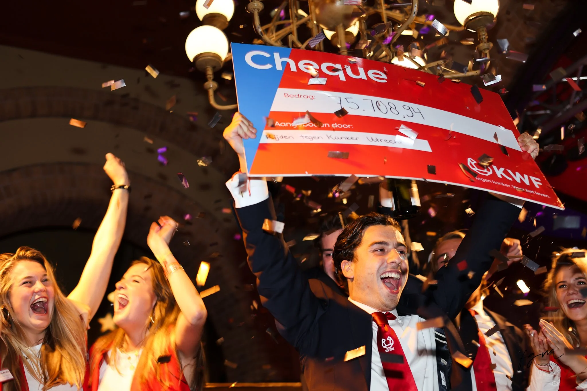Succesvolle veiling, een man houdt een grote cheque en confetti wordt uitgedeeld