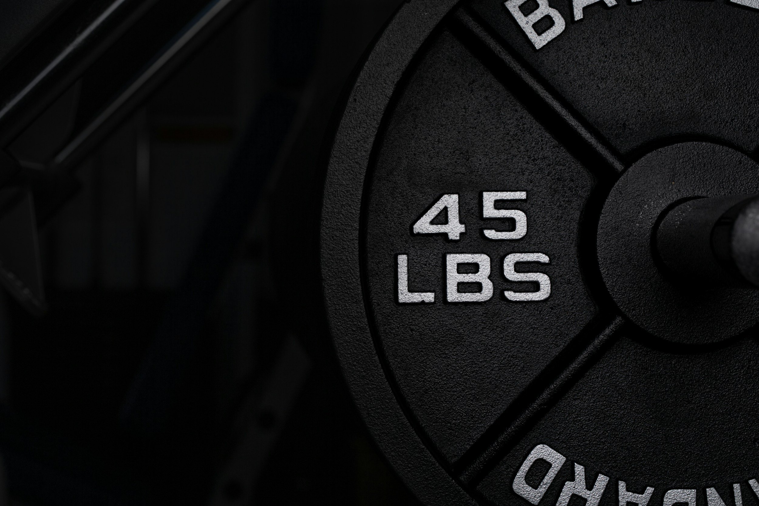 Close-up of a black weight plate with white numbers indicating 45 pounds.