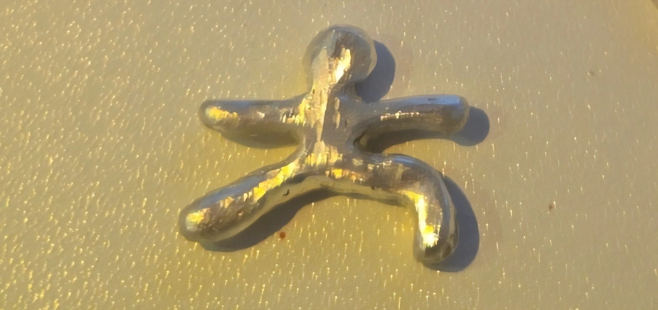 A silver and yellow butterfly-shaped object lying on a textured, yellowish surface.
