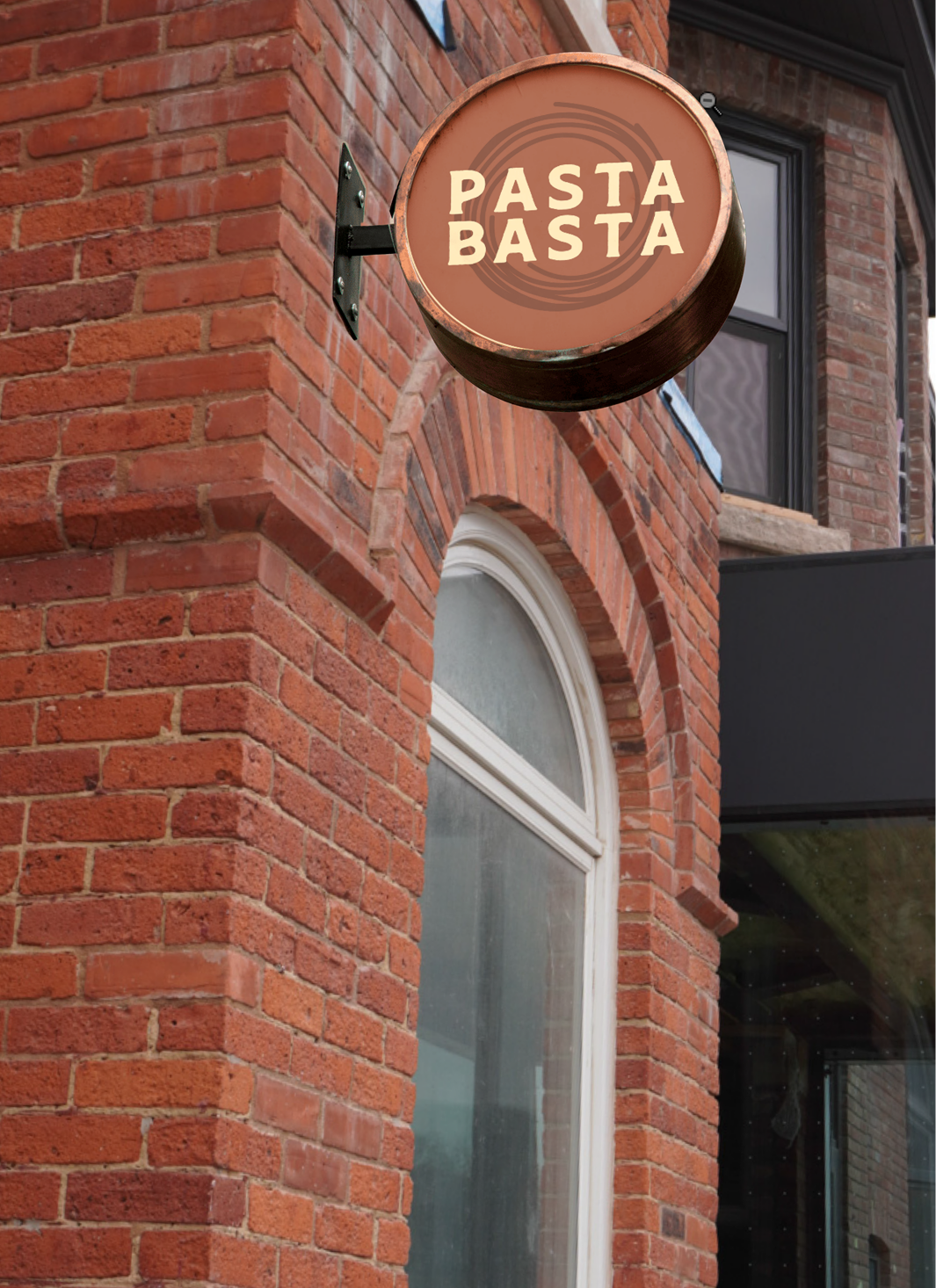 Signboard for Pasta Basta restaurant mounted on red brick building exterior.