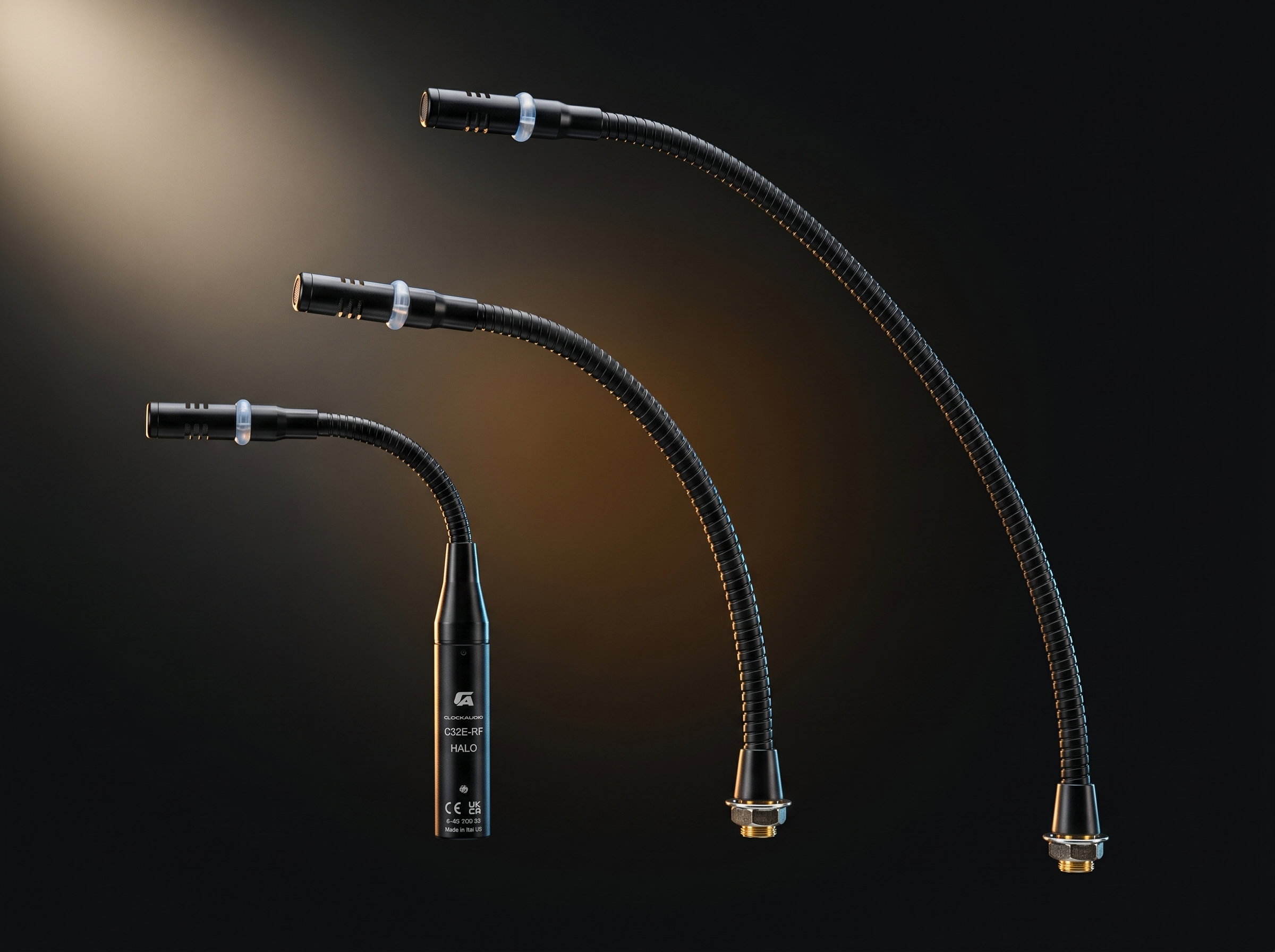 Three black gooseneck microphones with gold accents and black bases mounted on a dark background.