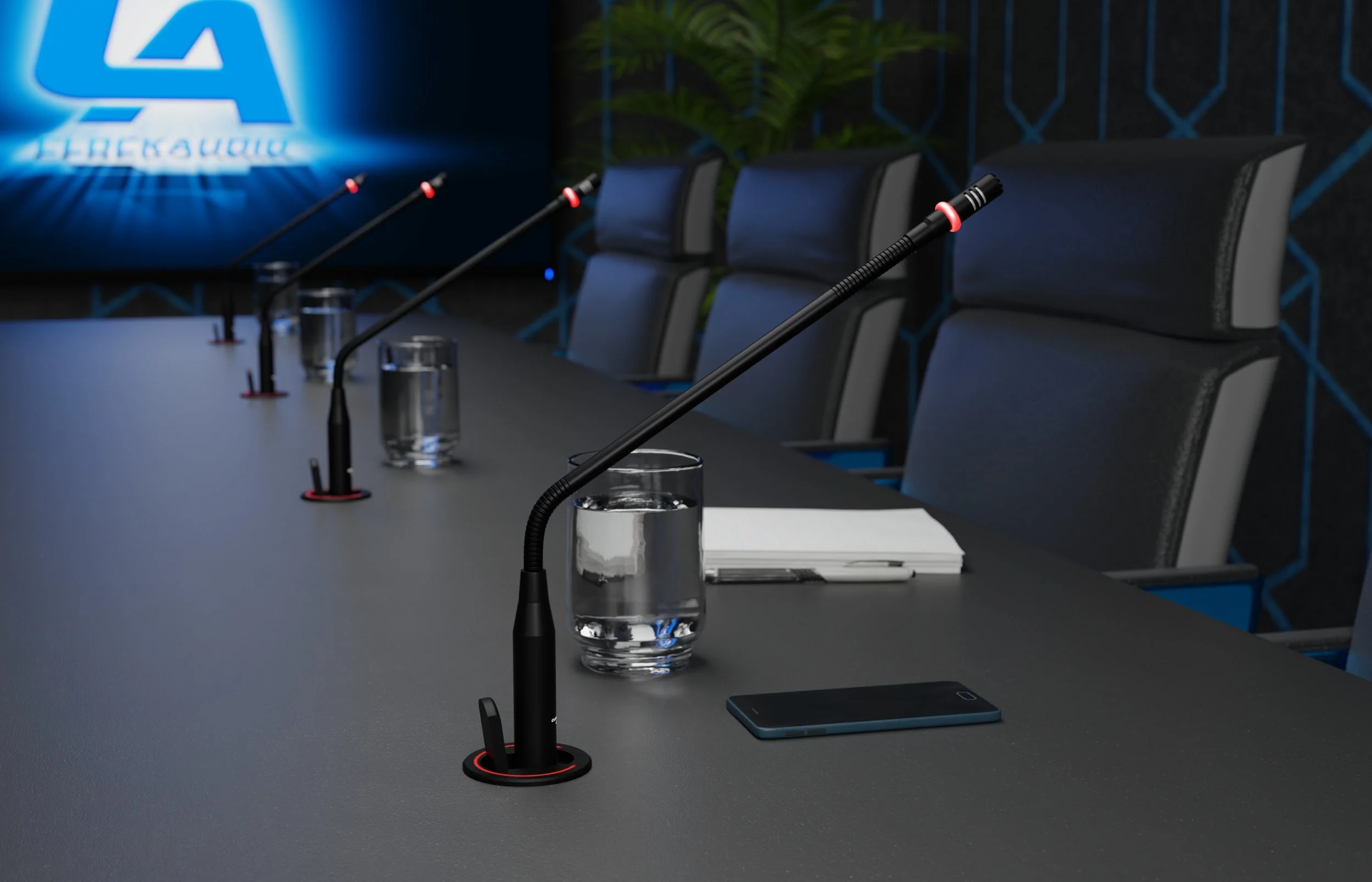 A conference room with a long table, black chairs, and microphones. There are glasses of water, notebooks, and a tablet on the table. A large blue COVID-19 symbol and text are projected on a screen at the front of the room.