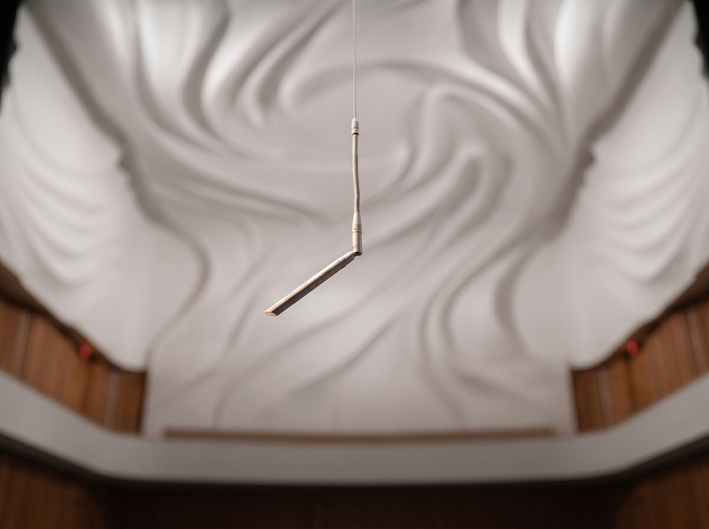Ceiling lighting with modern linear pendant light fixture in a room with curved and textured ceiling design.