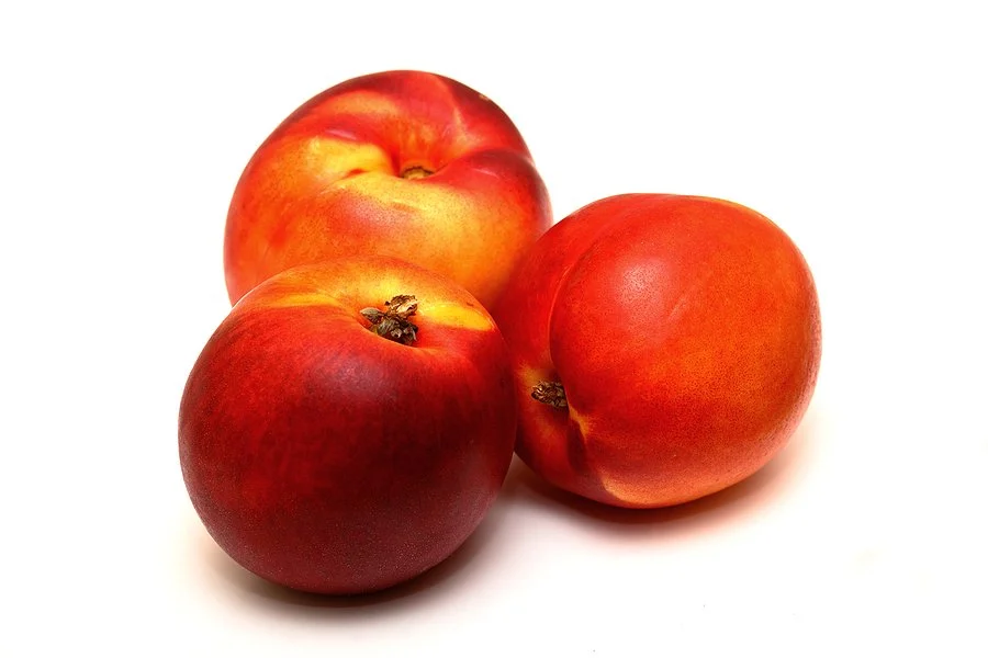 Three ripe nectarines on a white background.