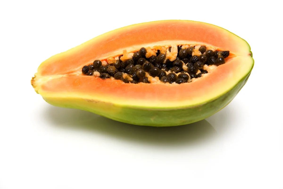 Half of a ripe papaya with seeds on a white background.