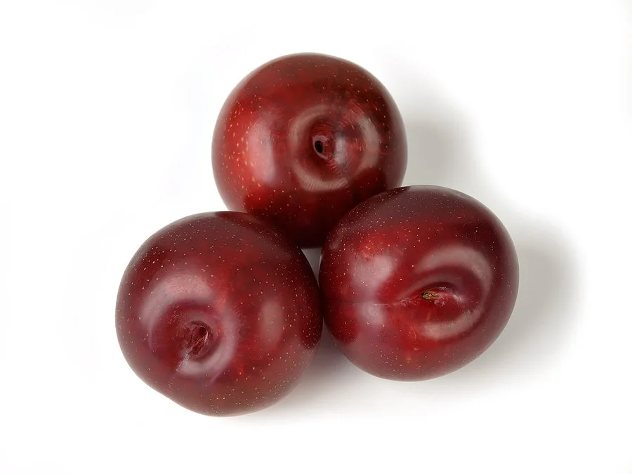 Three red plums on a white background.