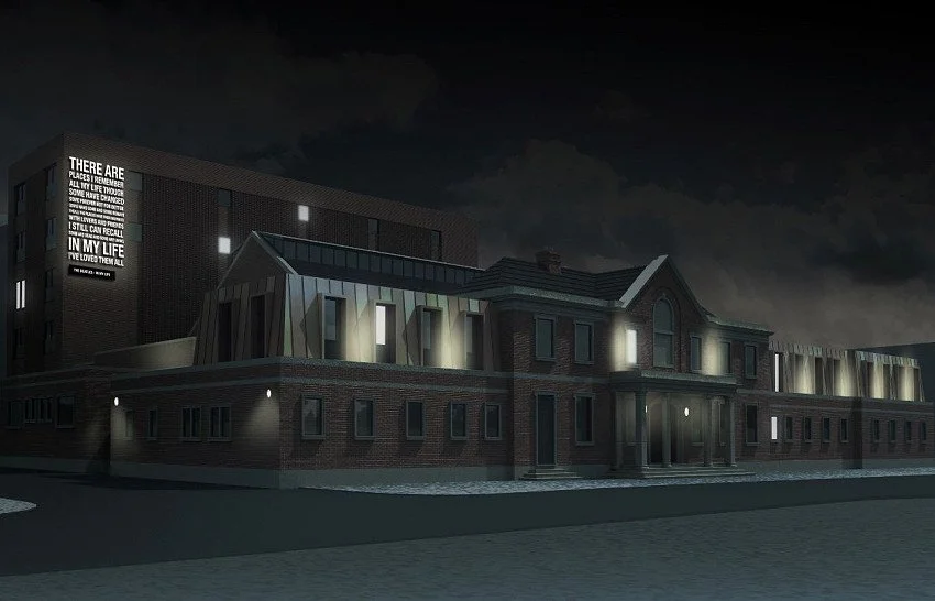 Nighttime view of a modern brick building with some illuminated windows and a sign on the upper left corner.