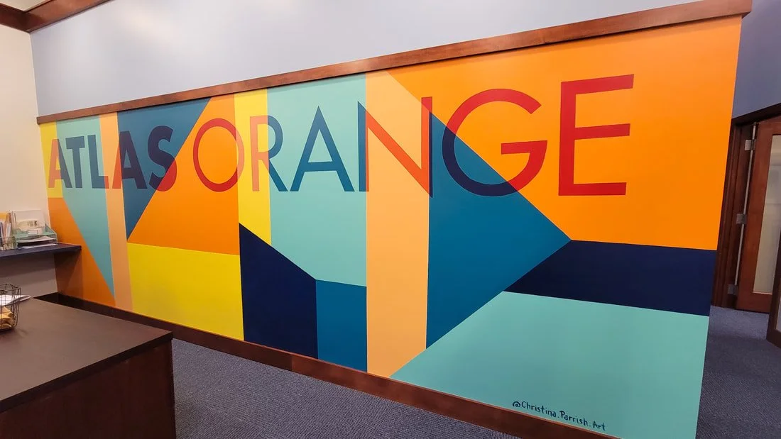 Colorful geometric mural with the words 'Atlas Orange' in bold letters on a wall.