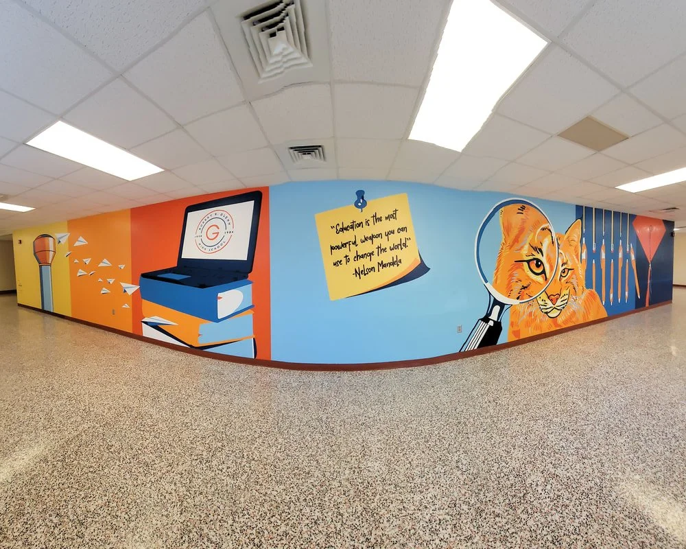 Colorful hallway mural with a laptop, books, a quote about education, and a cheetah looking through a magnifying glass.