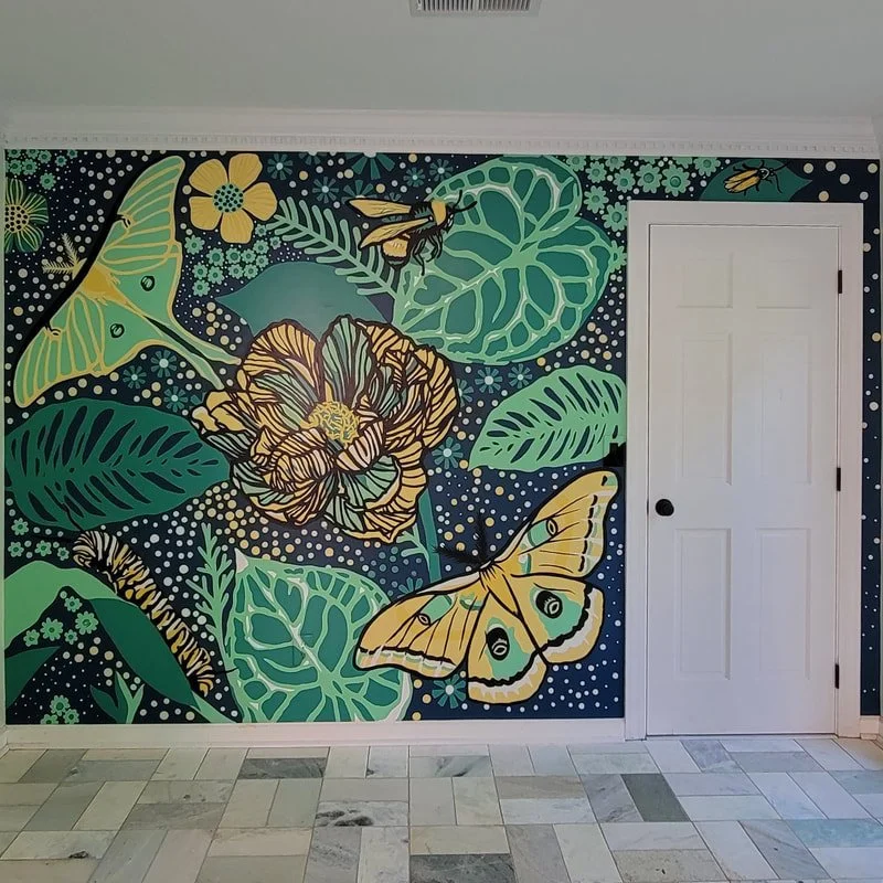 Colorful wall mural featuring large butterflies, flowers, and leaves in shades of yellow, green, and black with a dark background.