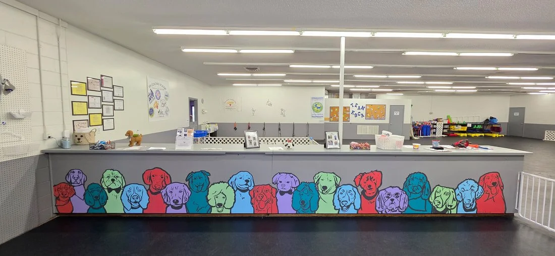 Colorful mural of dog faces on the front of a service counter in an indoor play area.
