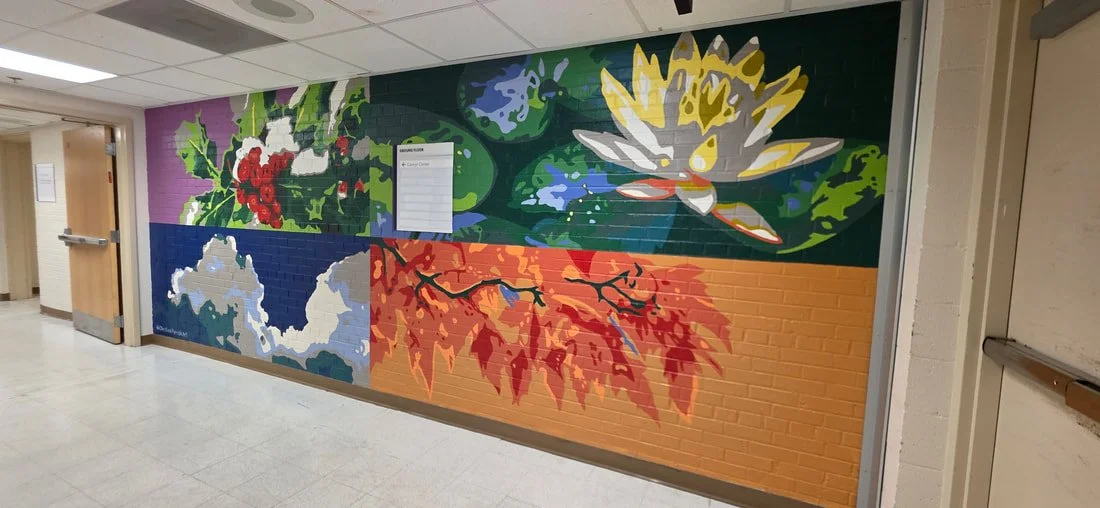 Colorful mural painted on a brick wall, featuring botanical designs including a large white and yellow flower, orange and red leaves, holly with red berries, and abstract green, blue, and lavender shapes.