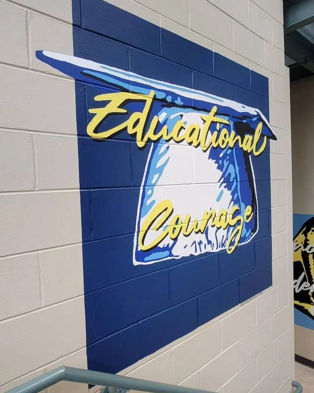 A mural on a wall features a blue bell with the words "Educational Courage" written across it in yellow cursive font.