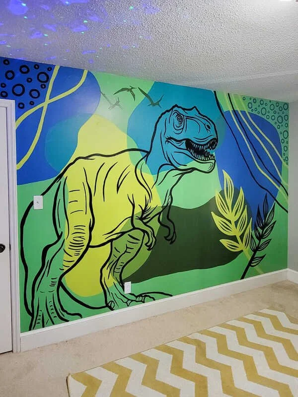Colorful mural of a Tyrannosaurus rex in green, blue, and yellow, with abstract background elements and plants.