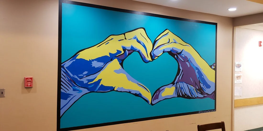Colorful mural of two hands forming a heart shape on a teal background.