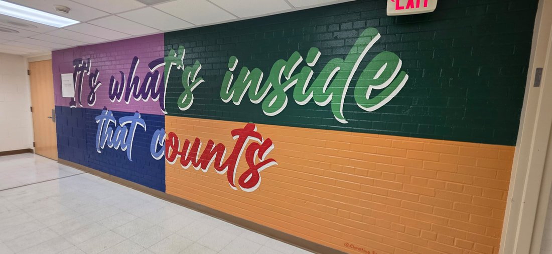 Colorful mural on a brick wall with the quote: 'It's what's inside that counts', in purple, green, blue, and red script fonts.