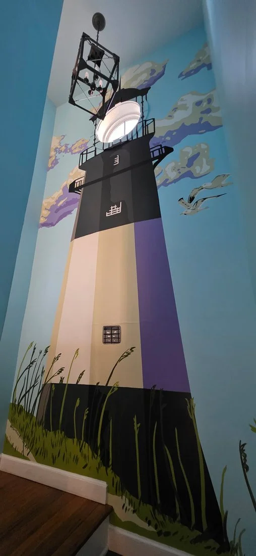 A tall, painted lighthouse with a black top, white and purple stripes, and small window near the bottom, located on a wall mural with grass and birds flying in the sky.