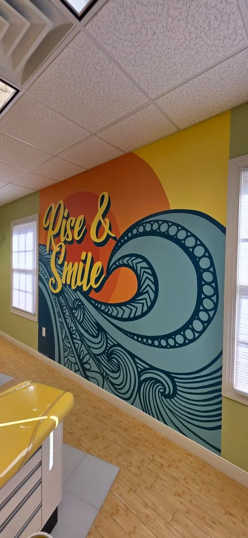 Colorful mural with the phrase 'Rise & Smile' in yellow on an orange and yellow background, featuring a large stylized wave design in blue and black.