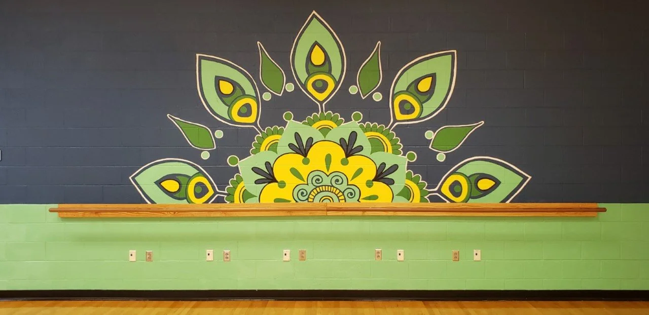 Colorful mural on a dark wall featuring green and yellow leaves and a yellow flower with black accents.