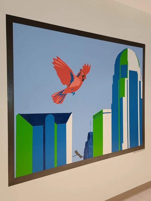 Digital artwork depicting a city skyline with tall buildings, two birds flying in the sky, one large red bird in the foreground and a smaller brown bird in the background.