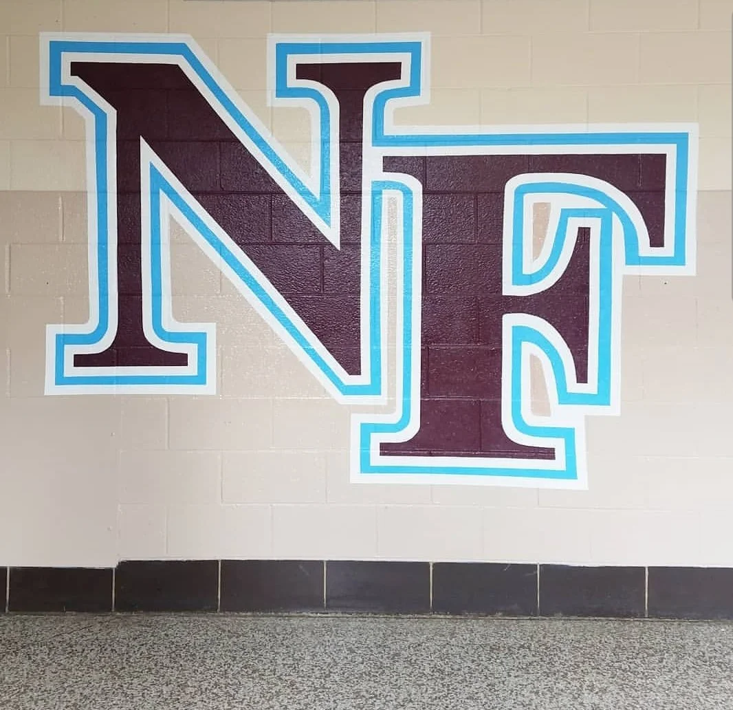 Large letter N and letter F logo painted on a beige brick wall with black and blue outlines.