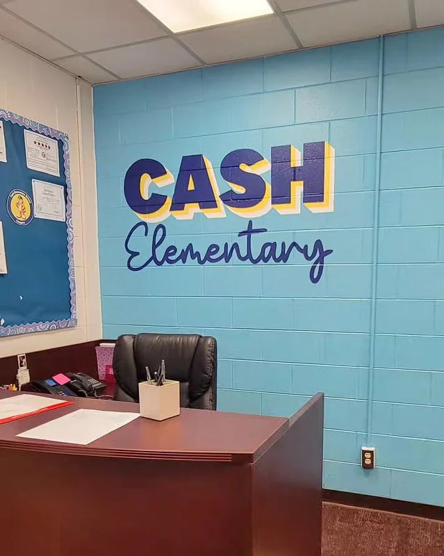 Decorated wall at Cash Elementary School with a blue background and colorful painted words.