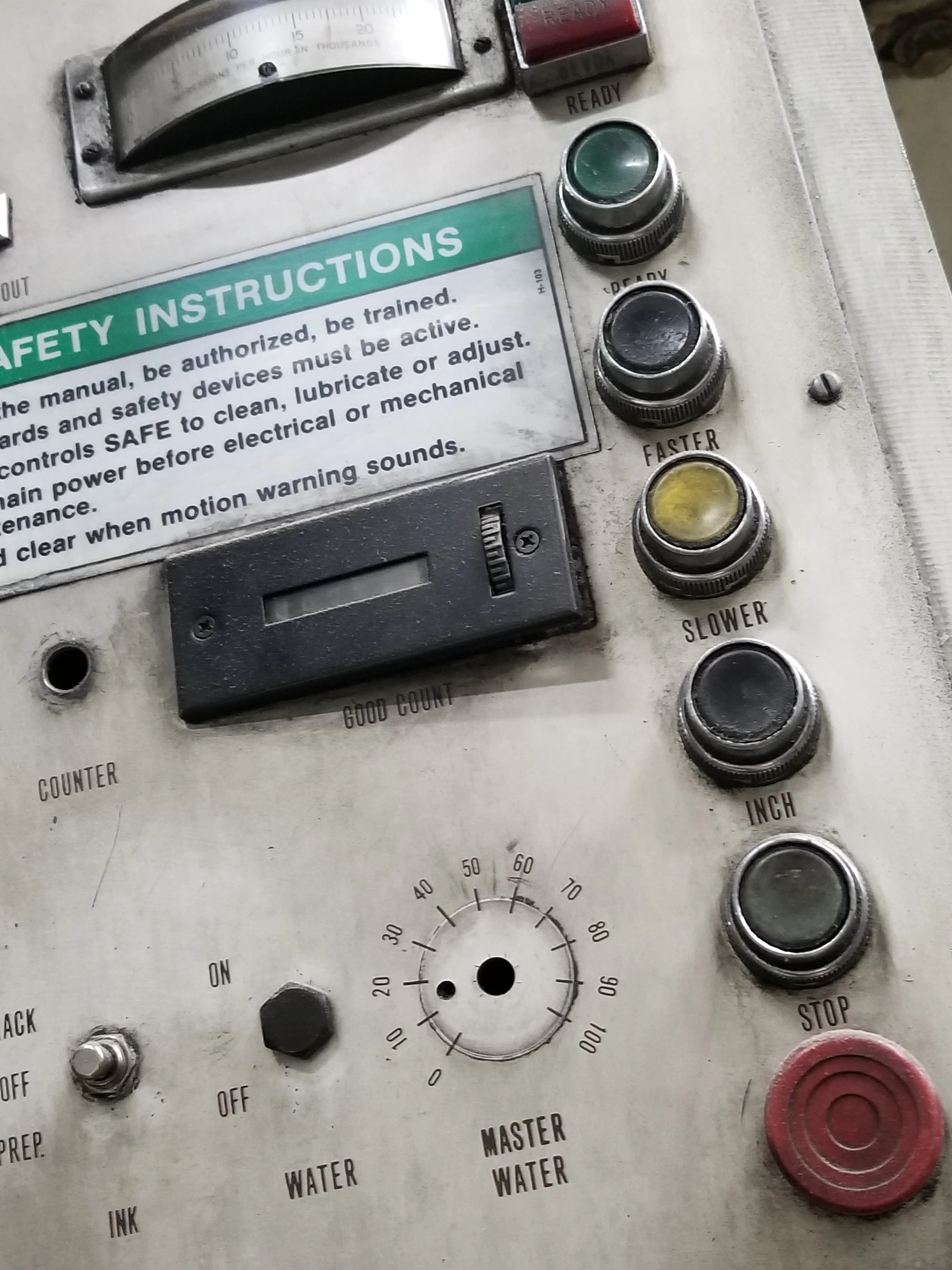 Close-up of an industrial machine control panel with safety instructions, buttons, and dials.