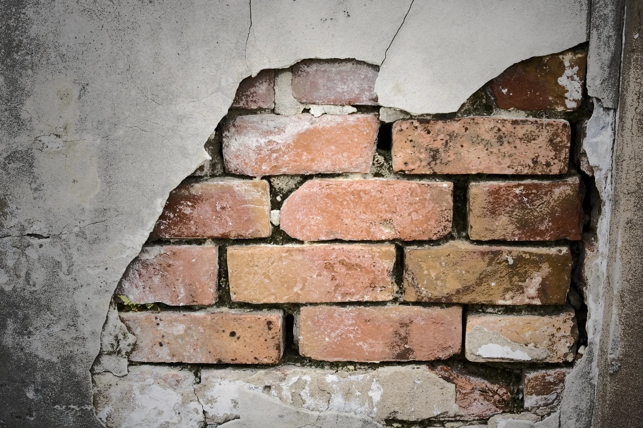Exposed old brick wall with cracked plaster
