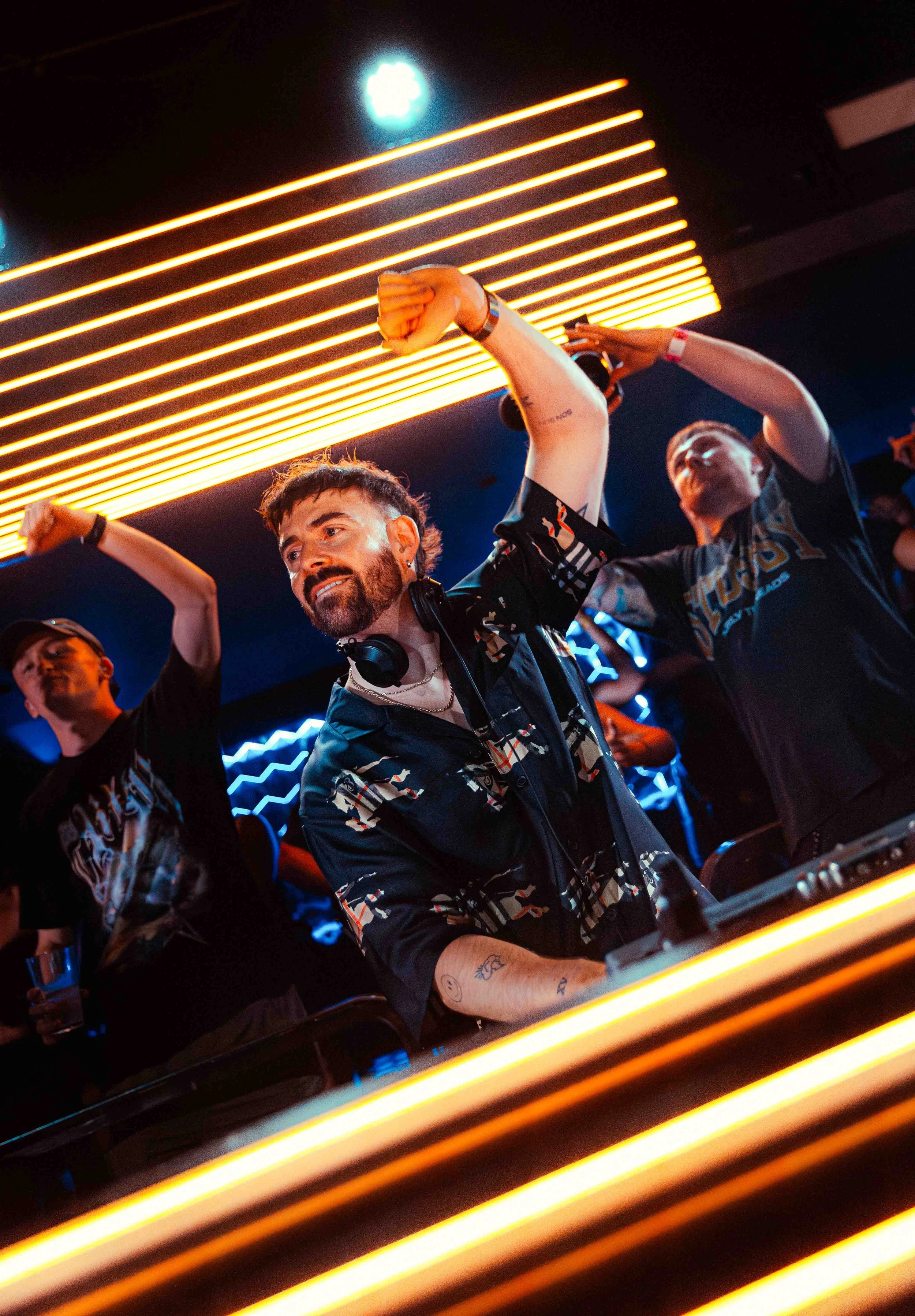 People dancing and enjoying music at a nightclub with neon lights.