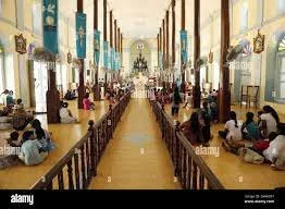 Interior of a church with pews, banners hanging from the ceiling, and people seated along the sides.