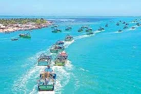 Boats moving across turquoise water near coastline