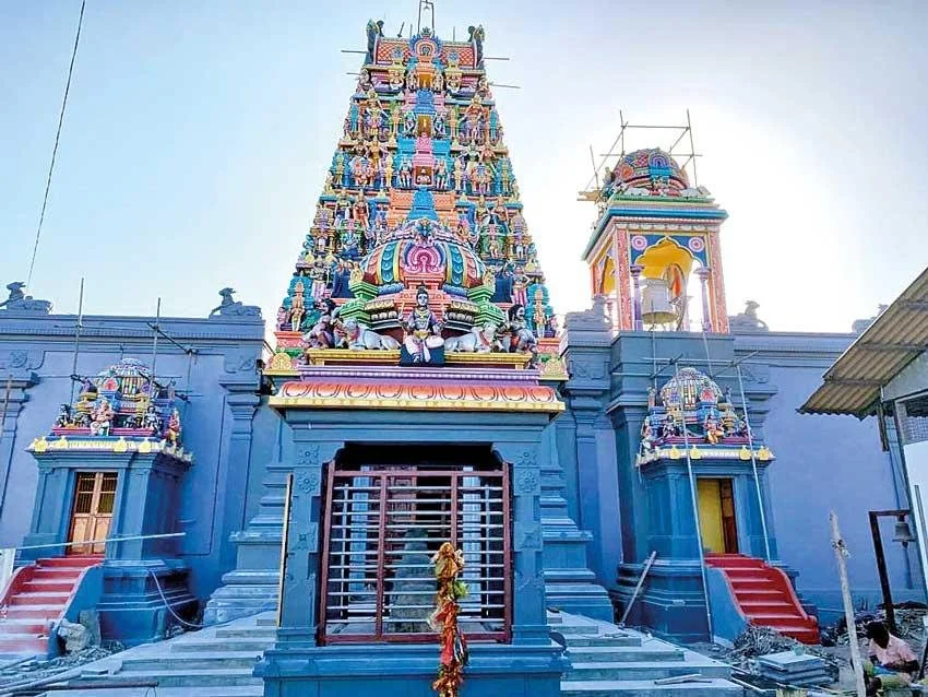 Colorful Hindu temple with tall, ornate tower and smaller structures, adorned with sculptures of deities and decorative elements.