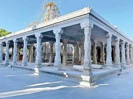 White marble temple with tall columns under a clear blue sky.