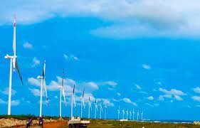 View of multiple wind turbines on open land under a blue sky with scattered clouds in Mannar.