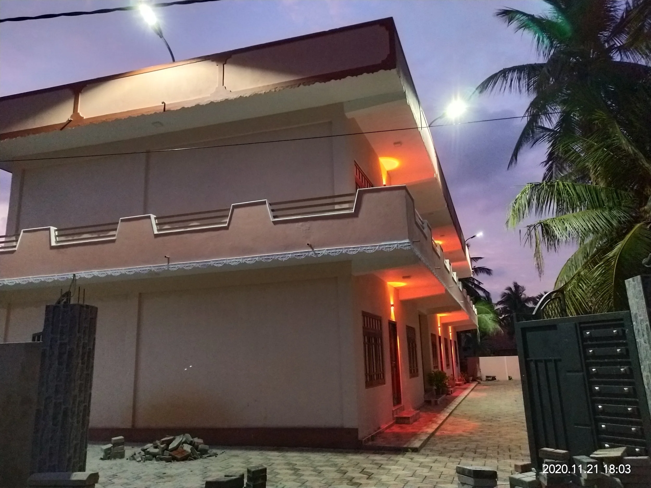 A multi-story residential building with illuminated balconies at night, set against a dark sky with some palm trees in the foreground. The timestamp on the photo indicates it was taken on November 21, 2020 at 6:03 PM.
