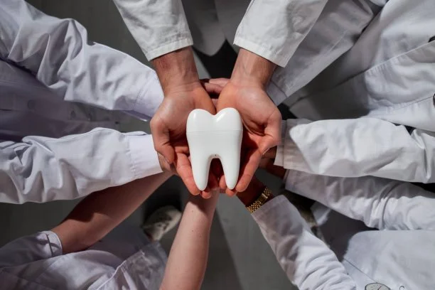Group of healthcare professionals holding a large tooth-shaped object together.