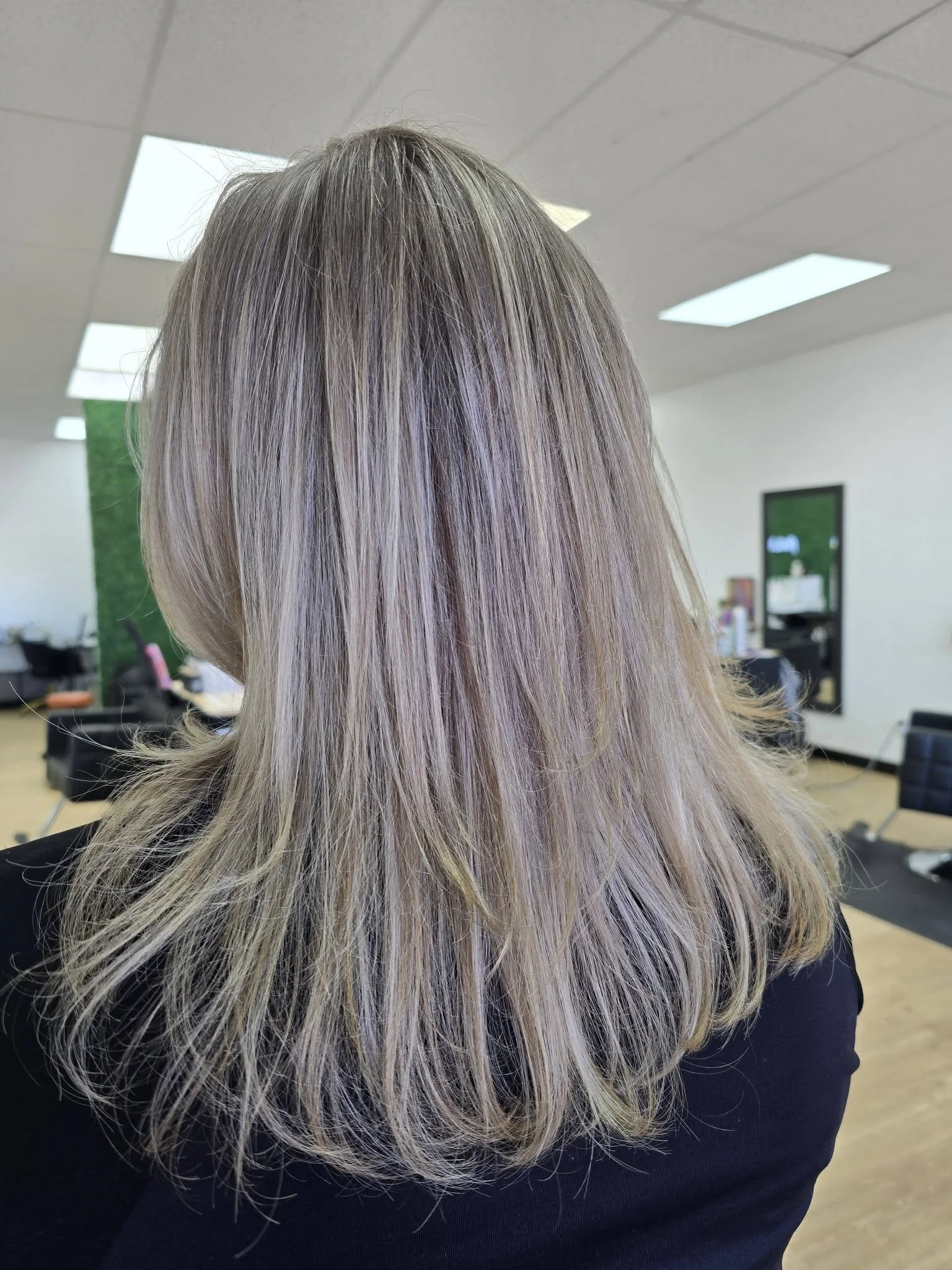 Close-up of a woman's long, wavy, ash blonde hair in a salon setting.
