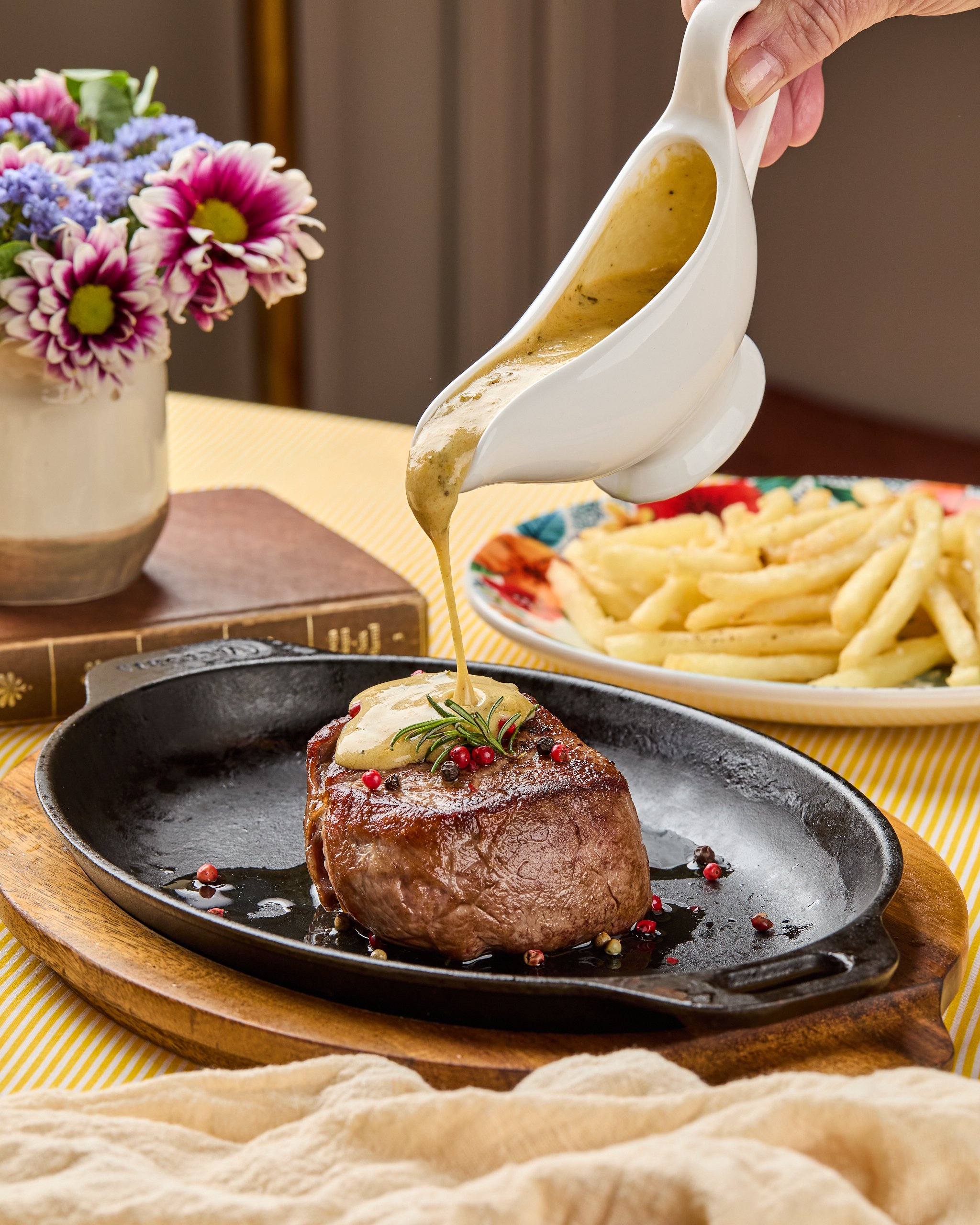 Fotografía gastronómica de plato con caída de salsa sobre un lomo pimienta, con papas a la francesa
