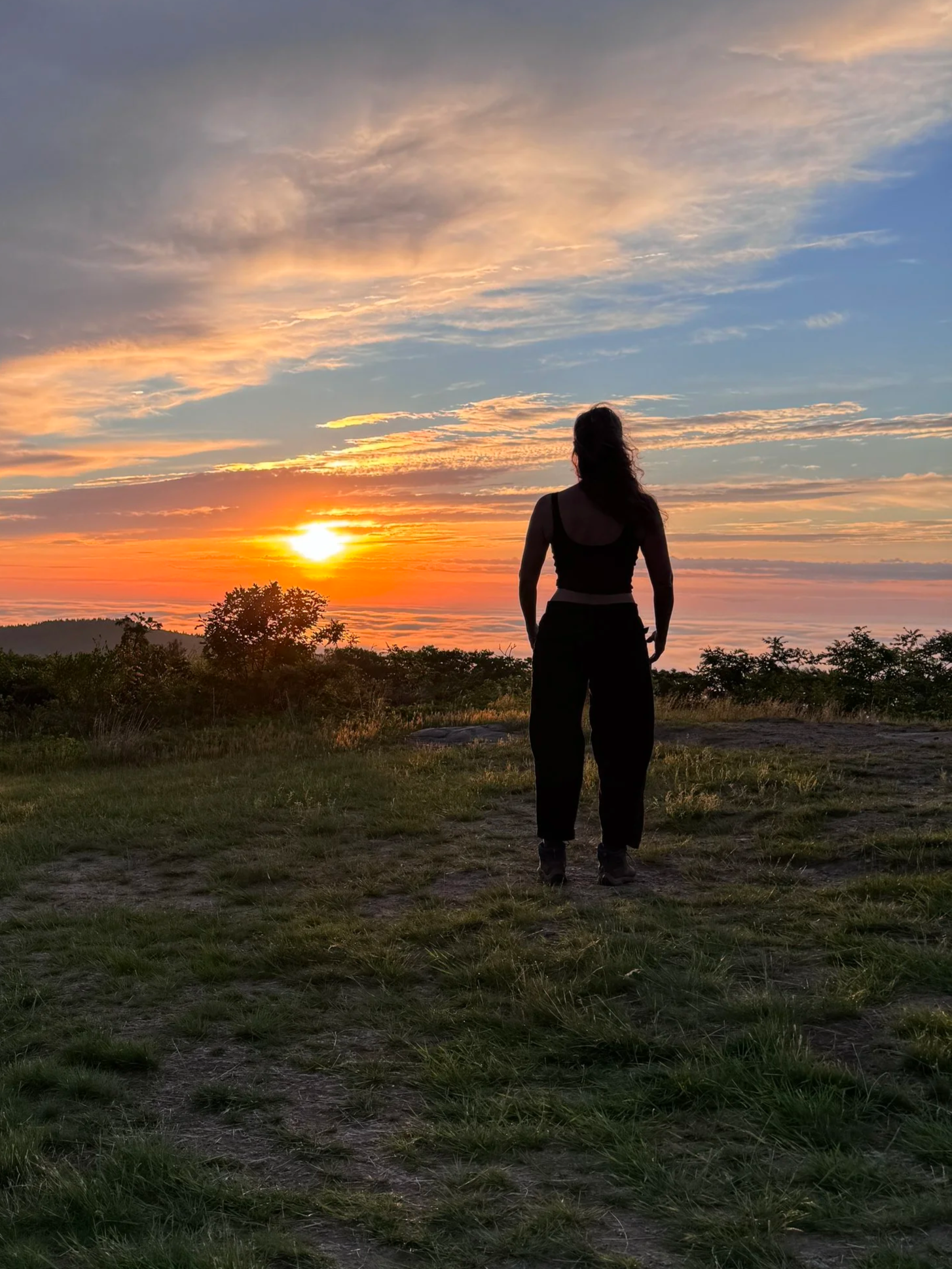 Erika walking outdoors at sunset beneath colorful evening skies.