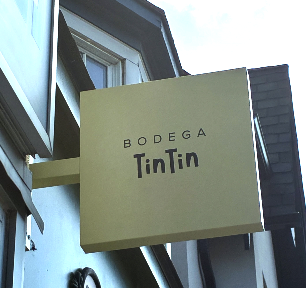 A yellow signboard with the words 'Bodega TinTin' mounted on a building exterior