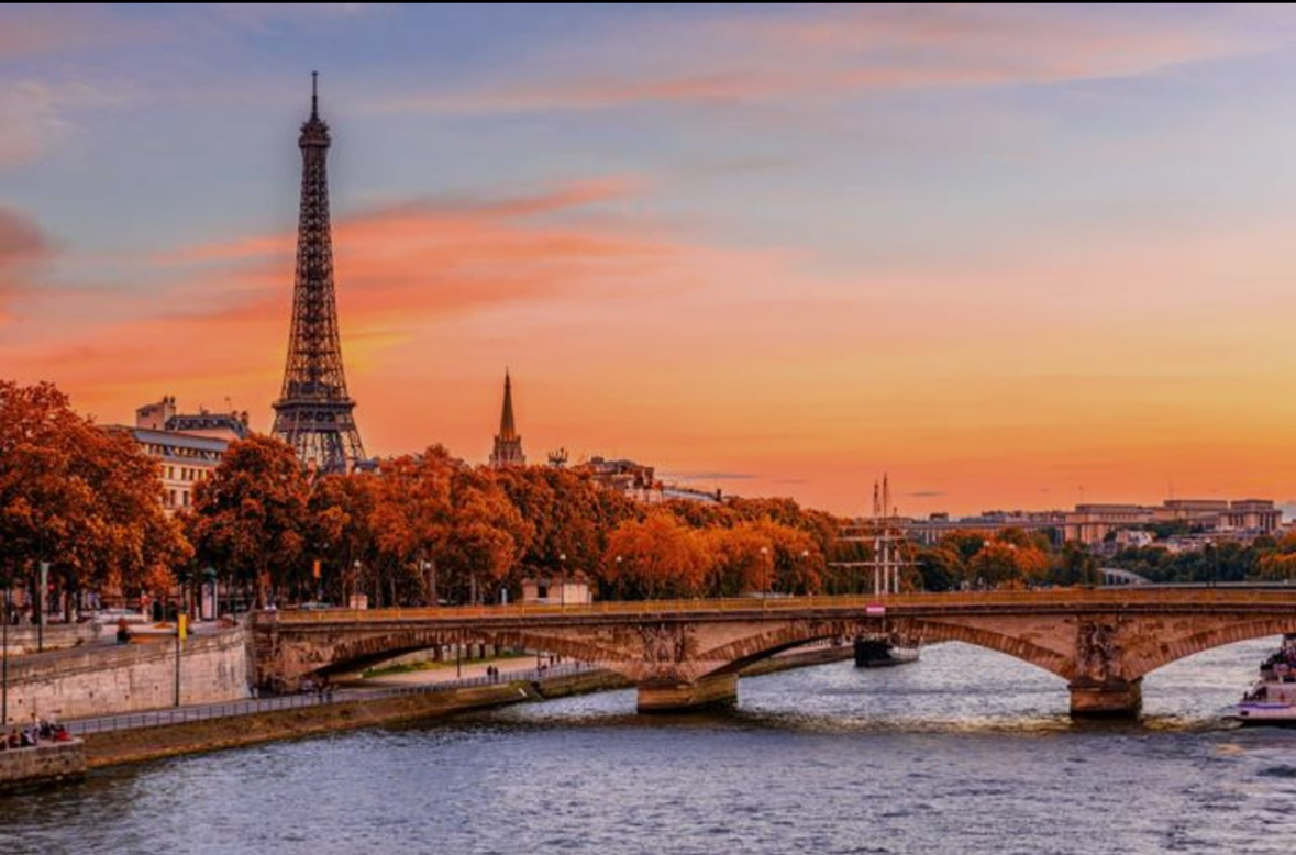 Sunset over the Seine River in Paris with the Eiffel Tower and a bridge.