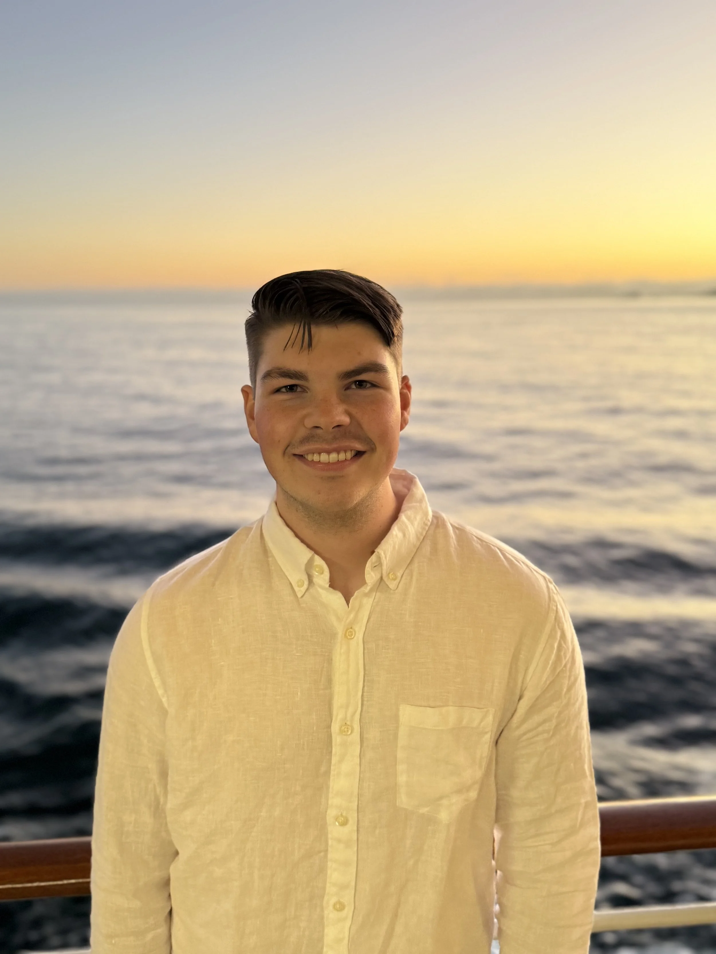a portrait of a man standing in front of the ocean