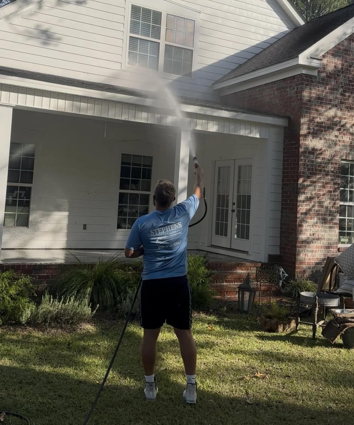 Bryce Stephens soft washing a home's siding and porch with a gentle soft wash spray — Stephens Exteriors house washing in Statesboro & Pooler, GA