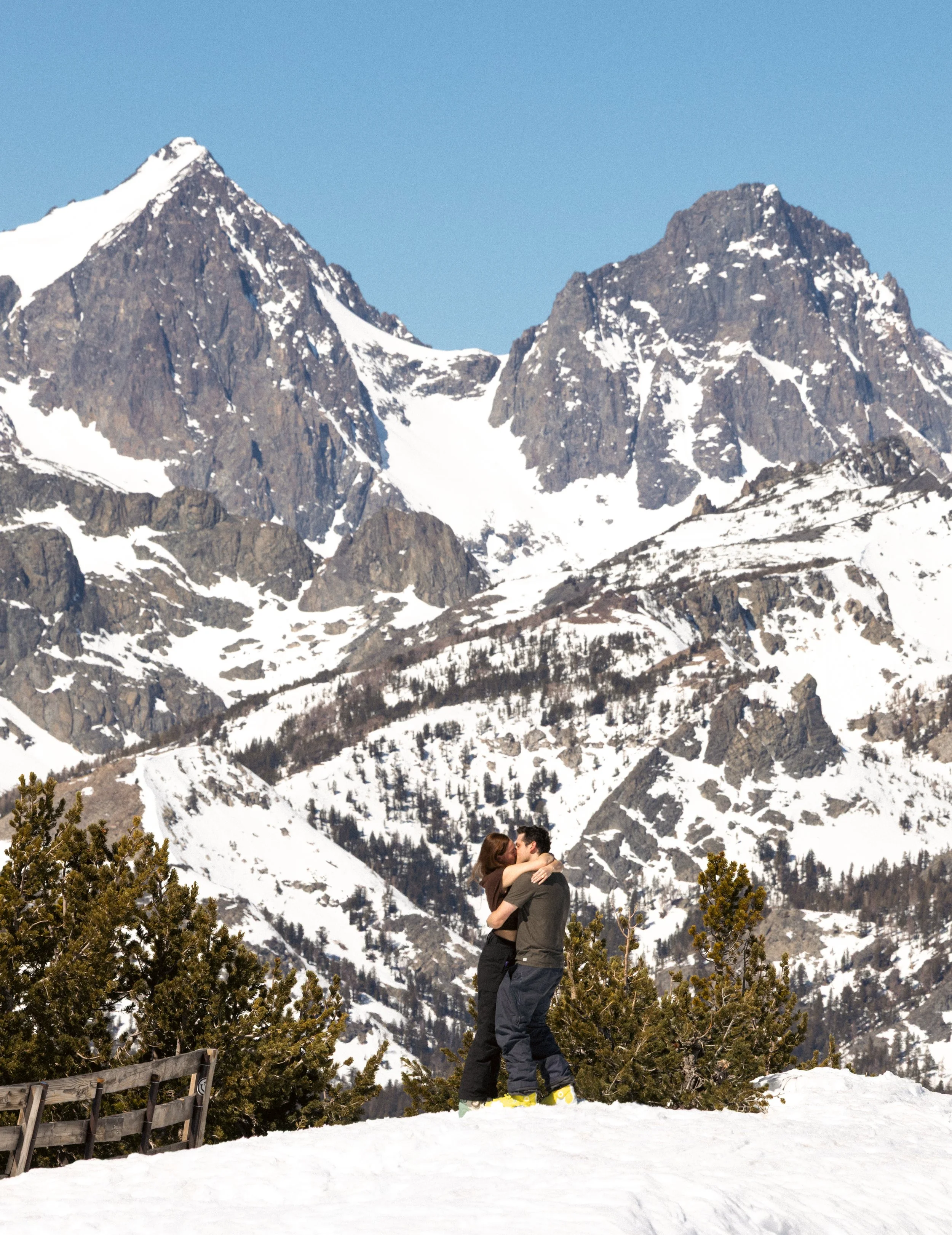A couple hugging and kissing because they just got engaged at mammoth mountain in the spring of 2026. I do 