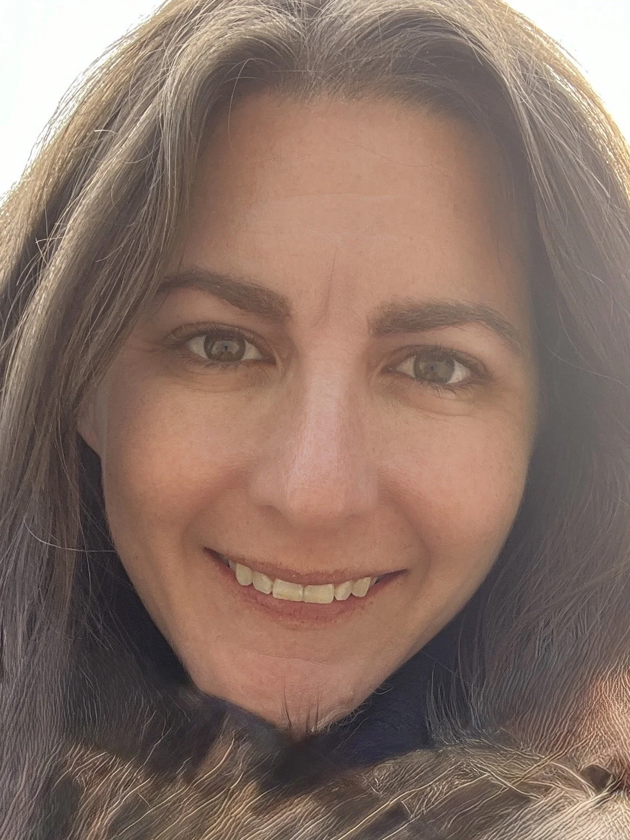 Woman with brown hair and eyes smiling at the camera