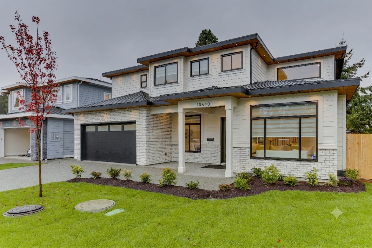Modern two-story house with white siding and large windows, a garage opening, and well-maintained front yard with small bushes, a young tree with red leaves, and hydration covers on the grass.
