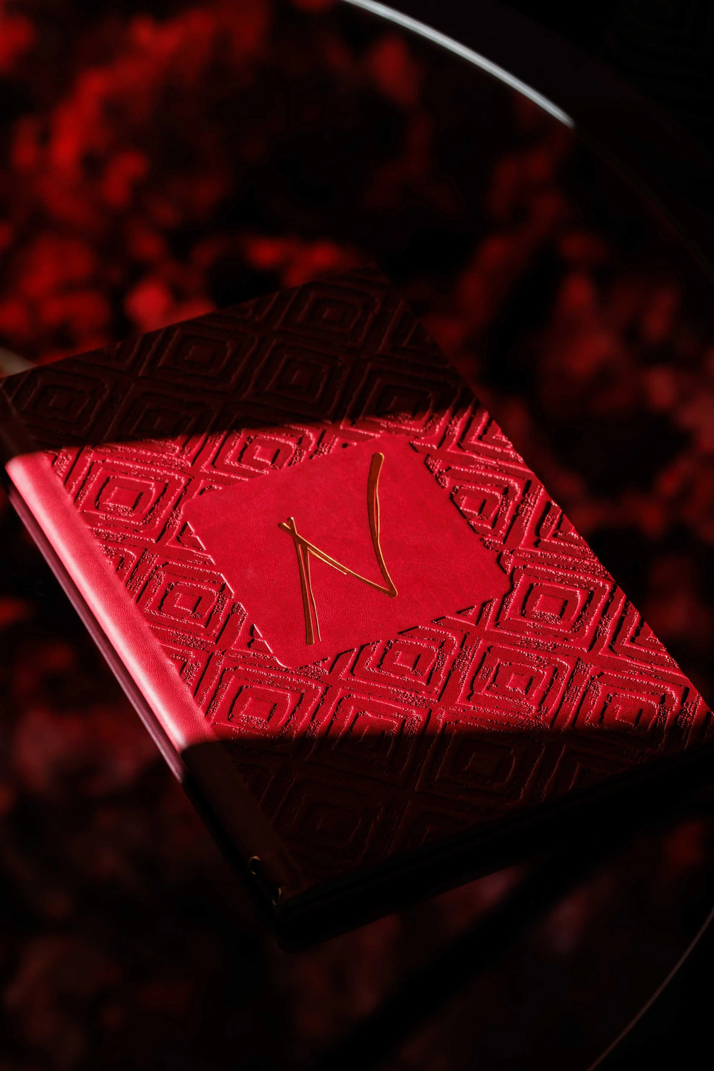 A red box with a geometric pattern and gold clock hands, set against a dark, textured background with red and black elements.