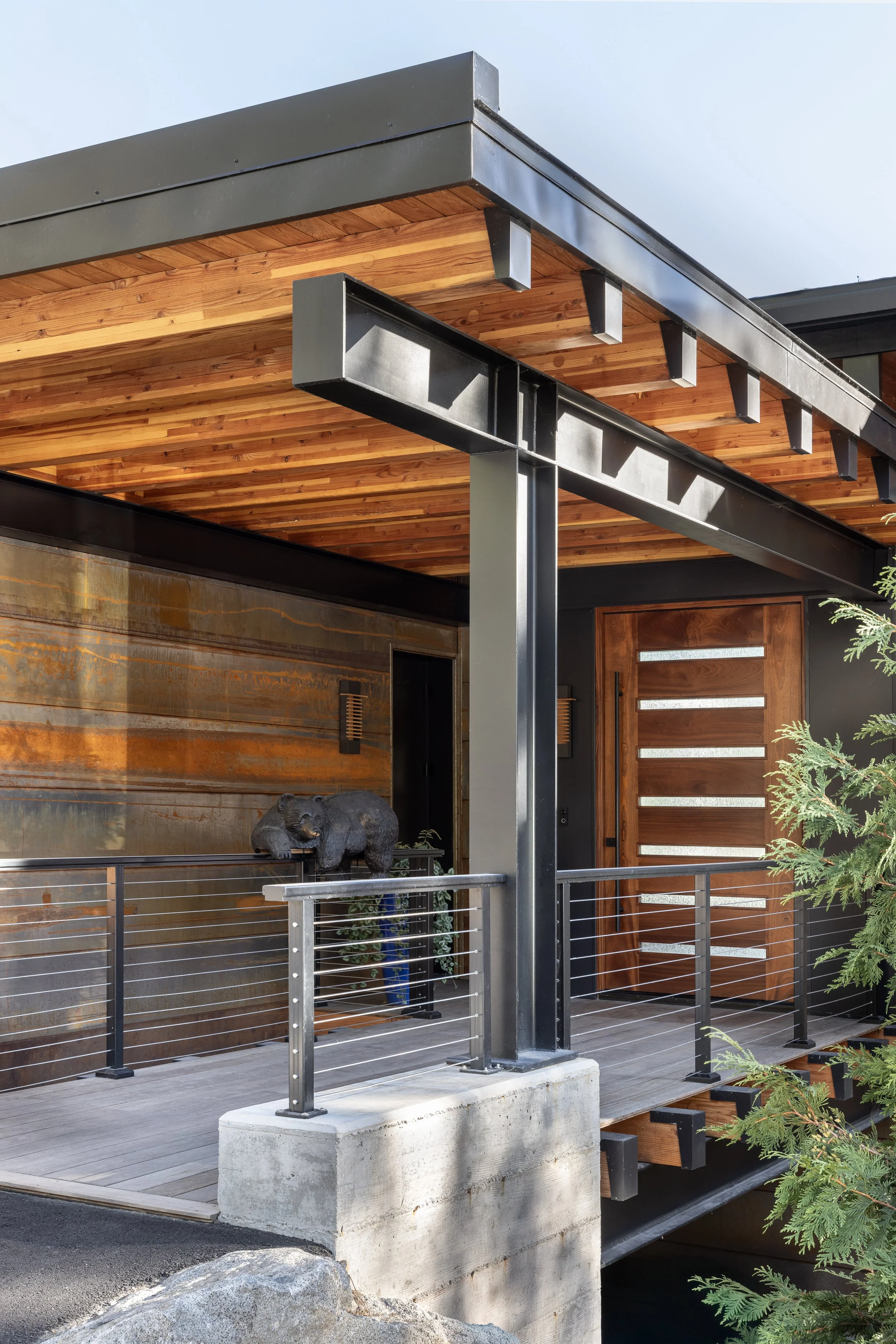 Exterior of a modern building with wood and metal architectural design, railing, and a decorative sculpture of a bear.