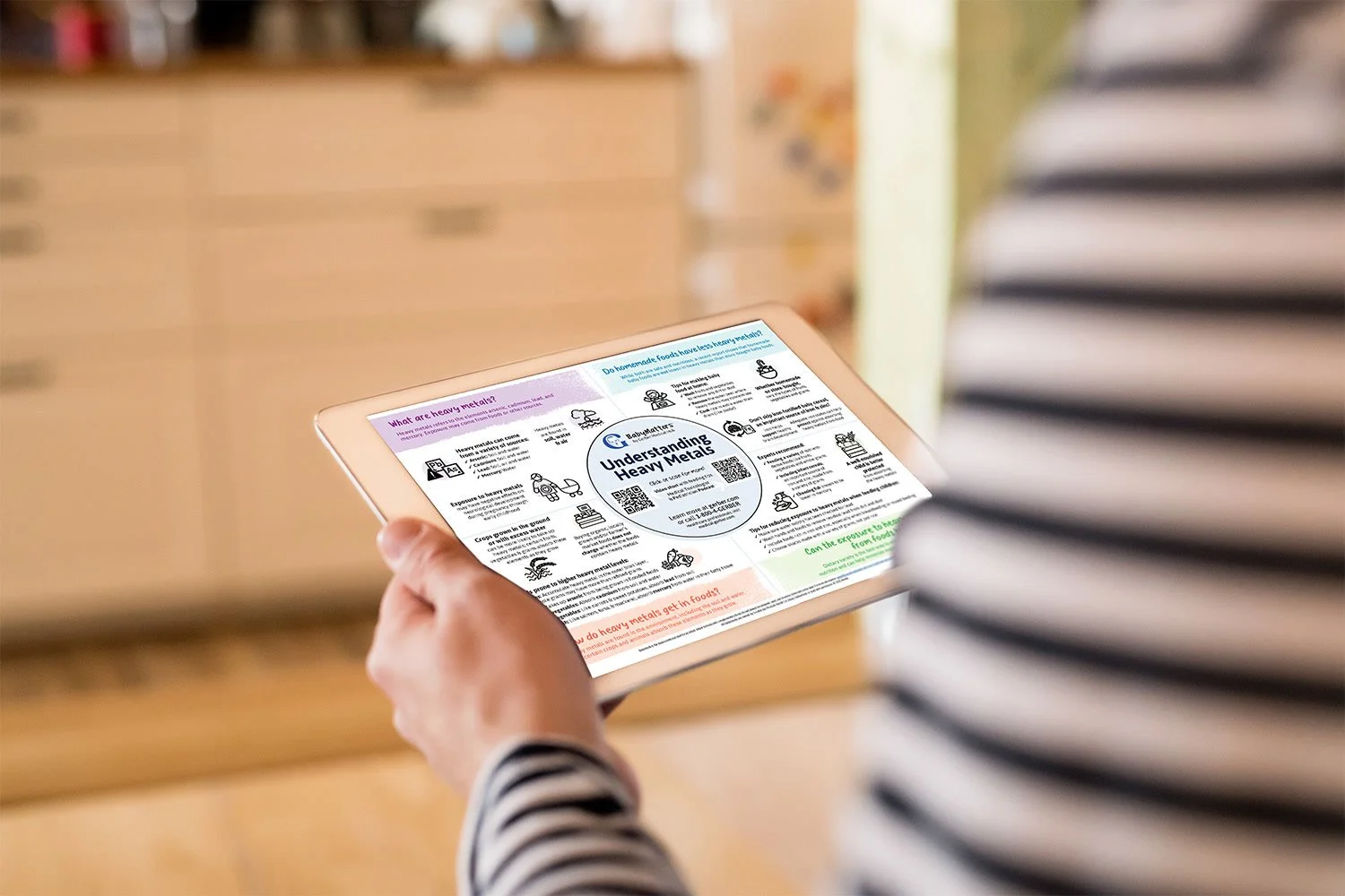 Person holding a tablet displaying an infographic on heavy metals in food, with a kitchen background.